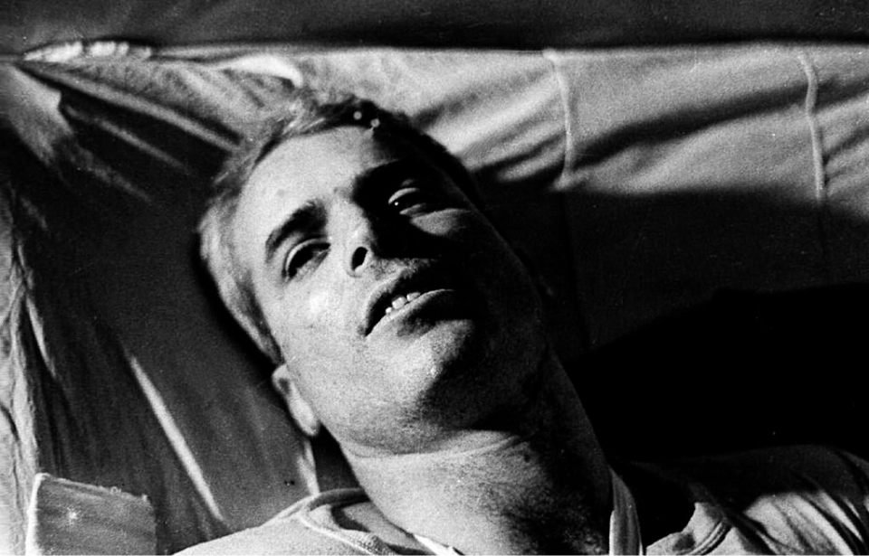 John McCain lying in a hospital bed