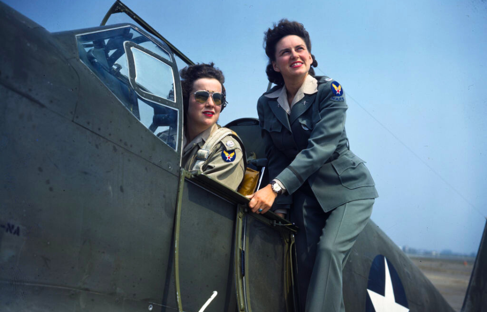 Barbara Jane Erickson sitting in the cockpit of an aircraft while Evelyn Sharp stands beside her